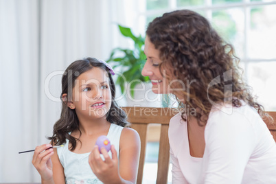 Happy mother and daughter painting easter eggs