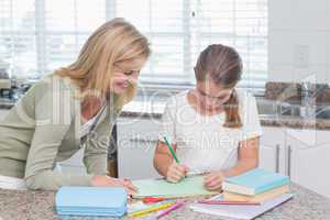 Happy mother helping daughter doing homework