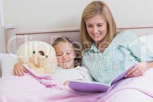 Happy mother and daughter reading a book