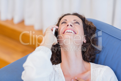 Smiling woman sitting on the couch and using her smartphone