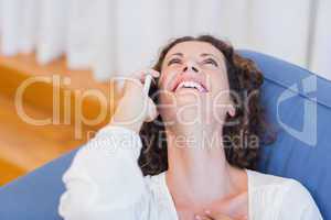 Smiling woman sitting on the couch and using her smartphone