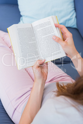 Casual woman reading book on couch