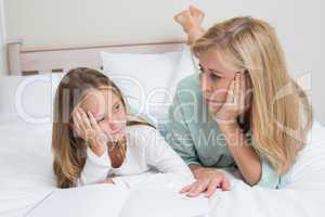 Bored mother and daughter reading a book