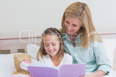 Happy mother and daughter reading a book