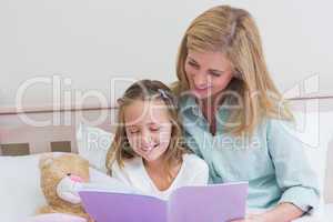 Happy mother and daughter reading a book