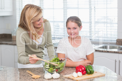 Happy mother and daughter preparing salad together