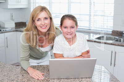 Smiling mother and daughter using laptop together