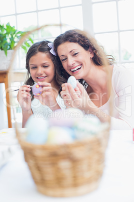 Happy mother and daughter painting easter eggs