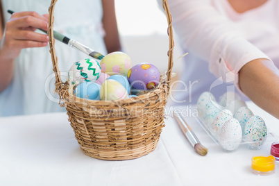 Happy mother and daughter painting easter eggs