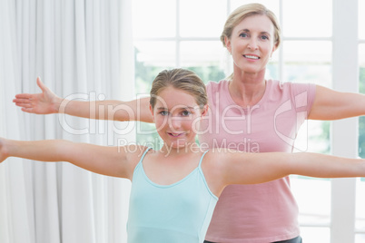 Happy mother and daughter doing yoga