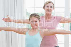 Happy mother and daughter doing yoga