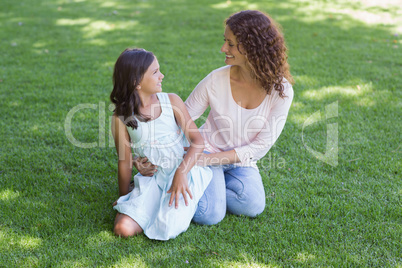 Happy mother and daughter sitting on the grass