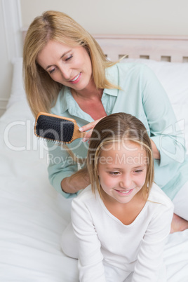 Smiling mother brushing her daughters hair Smiling mother brushing her daughters hair