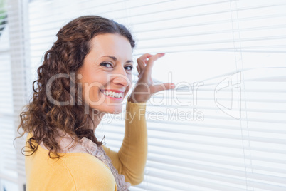 Curious woman looking through blinds