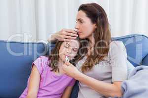 Mother taking temperature of sick daughter
