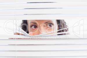 Curious woman looking through blinds