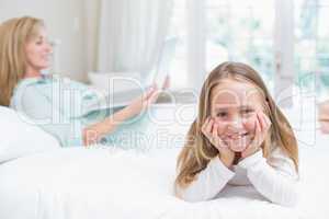 Little girl looking at camera while mother using laptop