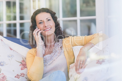 Pretty brunette relaxing on the couch and speaking on the phone