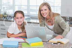 Happy mother helping daughter doing homework