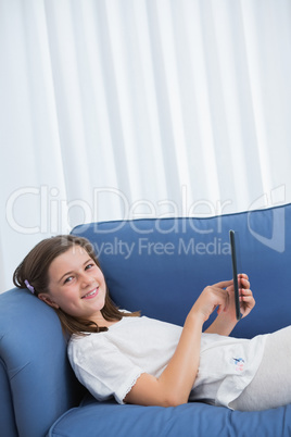 Little girl using digital tablet on the couch