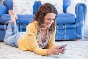 Pretty brunette lying on the floor and using smartphone