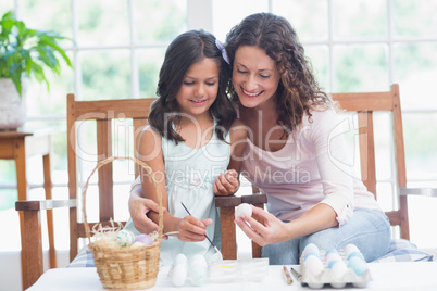 Happy mother and daughter painting easter eggs