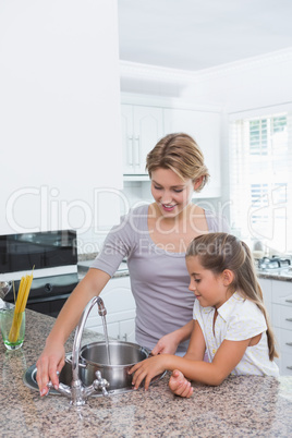 Mother and daughter filling pot with water