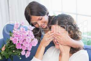 Smiling girl offering flowers to her mother