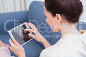 Casual brunette using tablet on couch