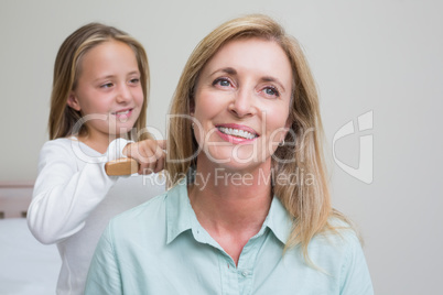 Cute girl brushing her mothers hair