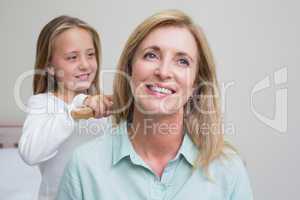 Cute girl brushing her mothers hair