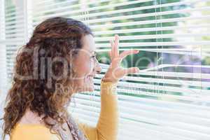 Curious woman looking through blinds