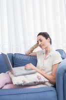 Casual brunette using laptop on couch