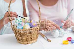 Happy mother and daughter painting easter eggs