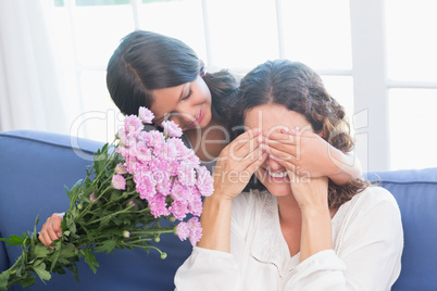Smiling girl offering flowers to her mother