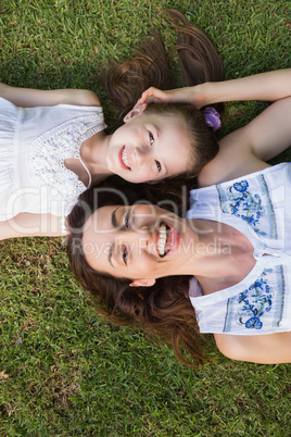 Mother and daughter lying on grass