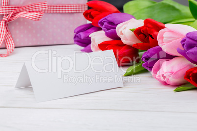 Colorful tulips and white card with present behind