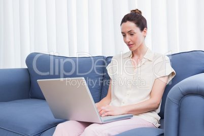 Casual brunette using laptop on couch