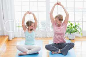 Mother and daughter doing yoga on fitness mat