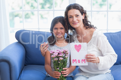 Cute girl offering flowers and card to her mother