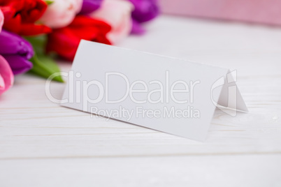 Colorful tulips and white card with present behind