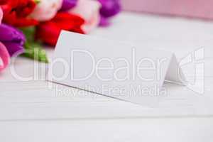 Colorful tulips and white card with present behind