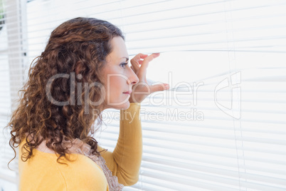 Curious woman looking through blinds