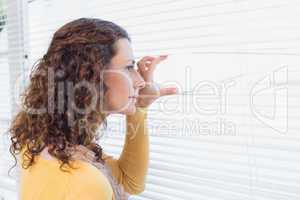 Curious woman looking through blinds