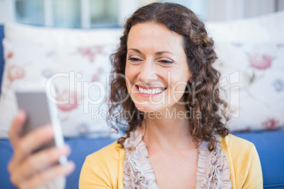 Pretty brunette sitting on the floor and using her smartphone