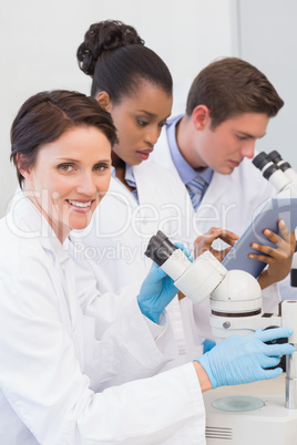 Scientists using microscope and tablet pc