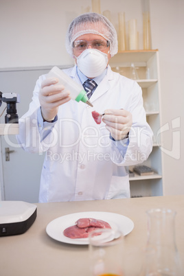 Scientist sprinkling fluid on meat
