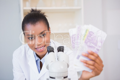 Smiling scientist holding money and looking at camera