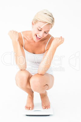 Happy attractive woman crouching on a scales