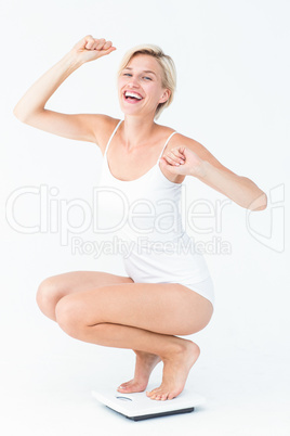 Happy attractive woman crouching on a scales